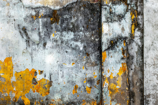 Aged weathered concrete wall with yellow and gray peeling paint texture
