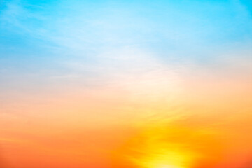Fototapeta premium Beautiful sunrise sky with vibrant gradient orange and gold colors and soft blue, Clear atmosphere with wispy clouds. Peaceful, perfect for background and copy space, High resolution images