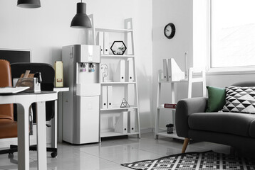 Fototapeta premium Interior of light office with workplace, shelf unit and water cooler