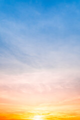Obraz premium Beautiful sunrise sky with vibrant gradient orange and gold colors and soft blue, Clear atmosphere with wispy clouds. Peaceful, perfect for background and copy space, High resolution images Vertical
