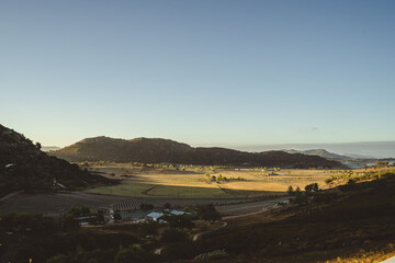 Obraz premium Aerial view of a sunny valley with rolling hills and farmland
