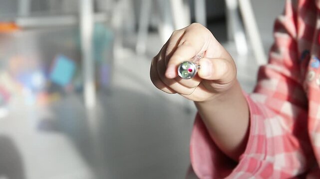 Child's Hand Operating a Toy Laser Pointer with a Bright Red Beam
