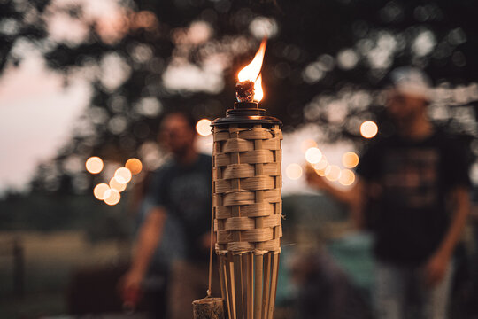 Tiki torch burning at outdoor evening party with bokeh background