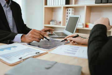Obraz premium Two business people are discussing and analyzing financial charts and reports at their desks in an office, with laptops nearby. The atmosphere is serious and professional.