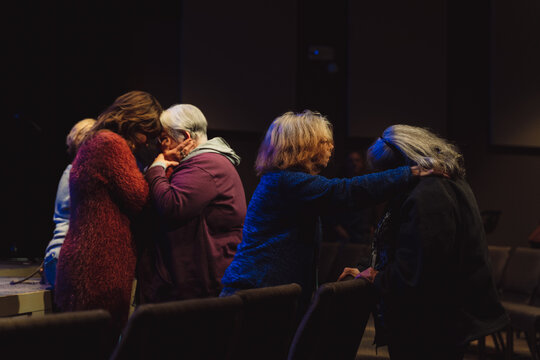 Group of women praying and offering support in a dark room