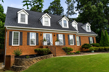 Two story red brick suburban house with five dormer windows