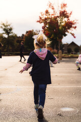 Obraz premium Rear view of young girl running on school playground in autumn