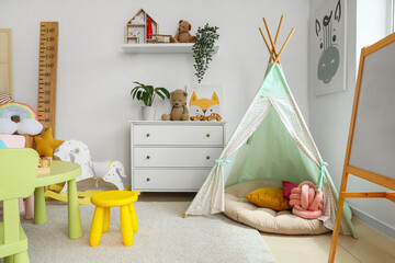 Interior of light playroom with toys, teepee and whiteboard in kindergarten © Pixel-Shot