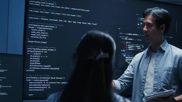Asian Male software engineer pointing at source code on a large screen during a tech team meeting, explaining Code on the Screen, Discussing on coding task, New software development project in office.