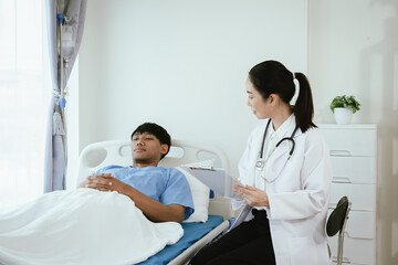 Obraz premium Female doctor reviewing medical records on a clipboard while a male patient rests in a hospital bed during inpatient care.