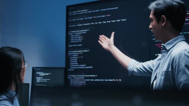 Male software engineer presenting a Coding Task, AI chatbot workflow with code on multiple monitors in a modern office. coding collaboration and agile projects Concept.