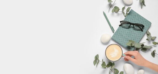 Female hand with cup of coffee, glasses, notebook, stones and eucalyptus branches on white background with space for text, top view © Pixel-Shot