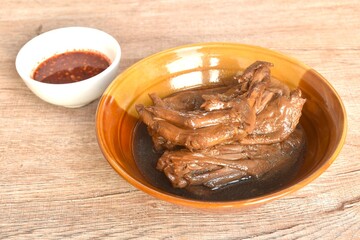 Fototapeta premium boiled slice duck foot and wing in black soybean herb soup in bowl dipping spicy sour chili sauce