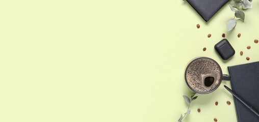 Cup of coffee, notebooks, earphones, beans and eucalyptus branches on light green background with space for text, top view © Pixel-Shot