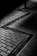 光と影が交差する路面タイルのモノクロ構図