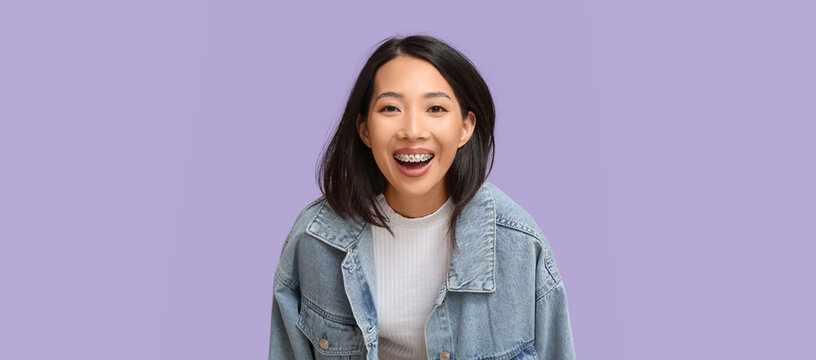 Young Asian woman laughing on lilac background