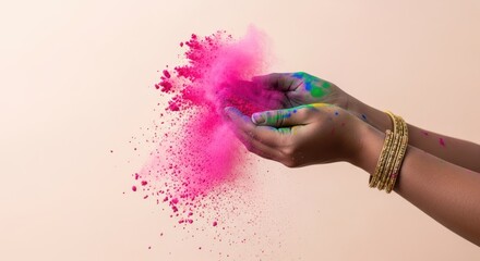 Hands cupping vibrant pink powder with splashes of color against a pale background
