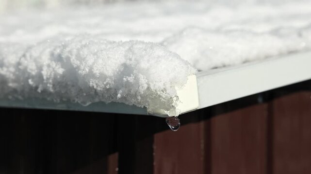 Close up view of melting snow dripping from roof edge in spring during warming. Sweden.