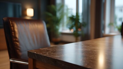 Close up of a textured marble desk surface in a softly lit office with a blurred leather chair and plants