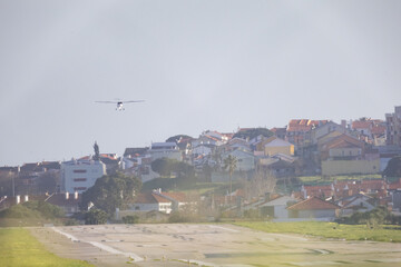 Fototapeta premium Small plane flying above urban houses