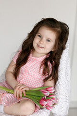 Naklejka premium Little girl with bouquet of pink tulips