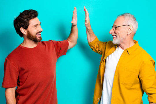 Two men high five smiling friends and family moment casual style on teal background