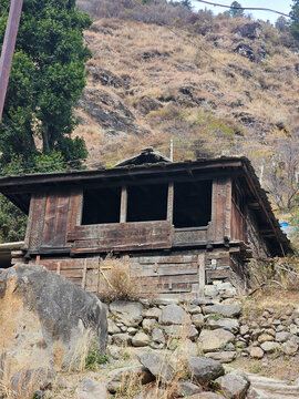 Vertical View of Antique Traditional Wooden House with Intricate Carvings Built on Steep Rocky Foundation in Himachal Pradesh India.