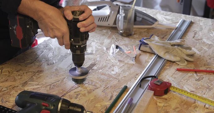 Carpenter - woodworker cuts hole through OSB plate using cordless drill and circular hole saw attachment 