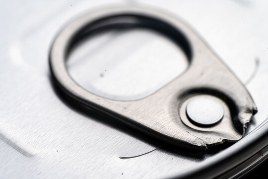 Close-up of a closed metal jar lid with an opening ring, on a white background, perfect for food packaging concepts.