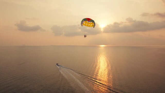 Parasailing during a spectacular sunset creating golden reflections on water