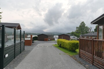 Fototapeta premium Scenic path through a holiday park with cabins and lush greenery on a cloudy day