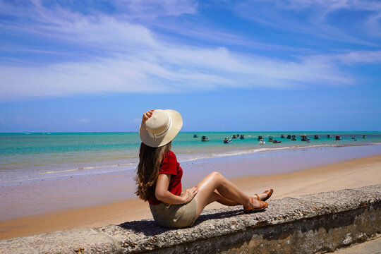 Traveler woman enjoying panoramic view of natural swimming pools with jangadas rafts in Joao Pessoa, Brazil