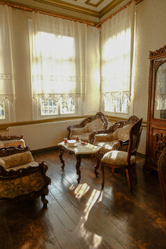 Cozy afternoon tea setup in a historic living room interior, featuring antique carved wood furniture, elegant marble table, and sunlight streaming through sheer curtains.