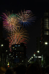 Vivid fireworks bursting over the city skyline and residential buildings at the Sumida River Fireworks Festival in Tokyo, Japan.
