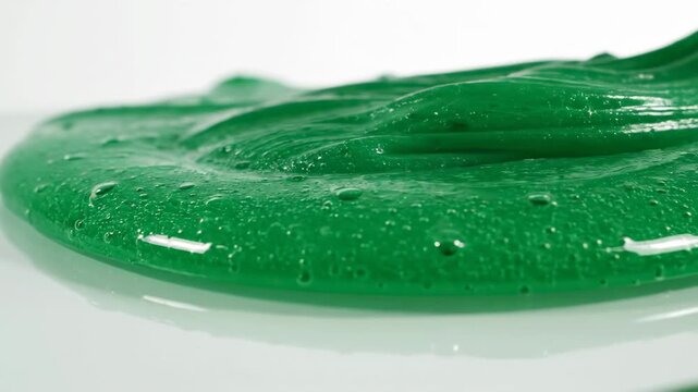 Green slime dripping onto a white surface, close up shot.