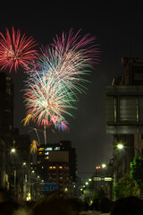 Vivid fireworks bursting over the city skyline and residential buildings at the Sumida River Fireworks Festival in Tokyo, Japan.