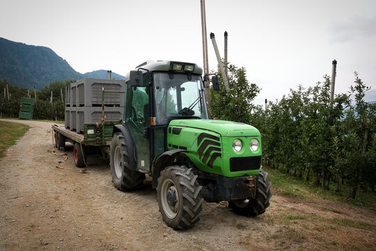 Ein gr&uuml;ner Deutz-Fahr Schlepper, Modell Agrocompact F100, mit einem Anh&auml;nger der mit grossen Kisten zur Apfelernte beladen ist