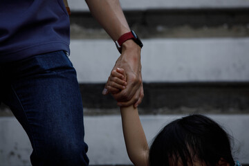 Father holding a child's hand walking down stairs, protection and care, hand skin texture, rear view close-up, at Wat Arun.