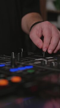Close up of DJ hand sliding volume fader on mixing console in dark club environment. Live electronic music performance and sound control concept.