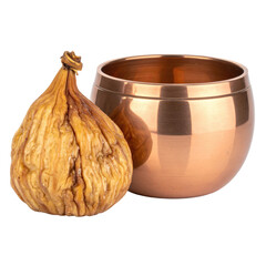 A dried fig sits beside a small, metallic bowl, both isolated on a black background