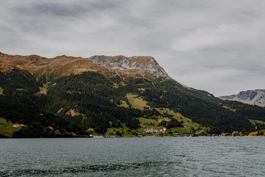 Panoramic view of Lake Reschen (Reschensee) and surrounding alpine mountains with a small shoreline village, South Tyrol, Italy