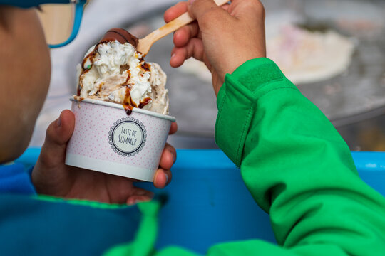 Unspecified - 09.02.2026: Child holding a cup of ice cream with chocolate sauce and whipped cream