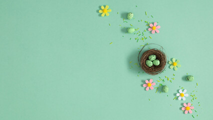 Easter nest with speckled green eggs on mint background with pastel flowers, top view, spring holiday celebration composition Easter with copy space for text, flat lay concept for greeting card design © prime1001