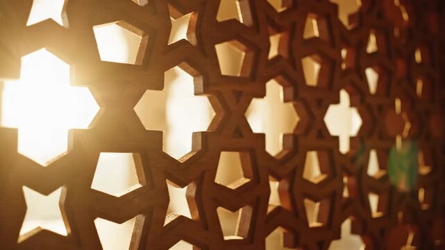 Detailed wooden screen with intricate geometric Islamic pattern illuminated by warm light.