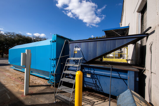 Industrial trash compactor outside warehouse
