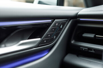 Close-up of car door panel with seat memory buttons and door lock control. Focus on luxury...