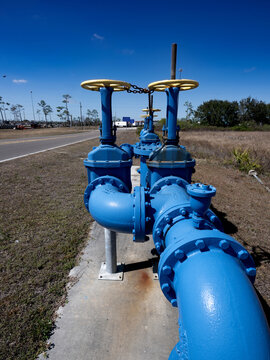 Main blue water pipes line for potable drinkable water outside over grass pasture and road next to it