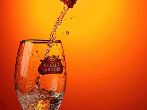 Stella Artois beer pouring on a glass of the same brand.
