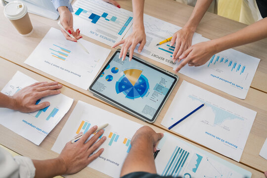 Business team analyzing financial charts and marketing data on digital tablet during corporate meeting, collaborative strategy planning with analytics reports, teamwork discussion, modern office produ