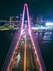 modern cable-stayed Thu Thiem suspension bridge over Saigon river with colourful illumination neon led lights, symmetric perspective and design, Ho Chi Minh city, Vietnam aerial drone view